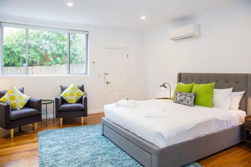 a bedroom with a large bed and two chairs at Esperanza Gardens - A Stylish Victorian Studio in Sydney