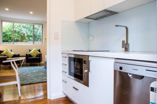 a kitchen with a sink and a dishwasher at Esperanza Gardens - A Stylish Victorian Studio in Sydney