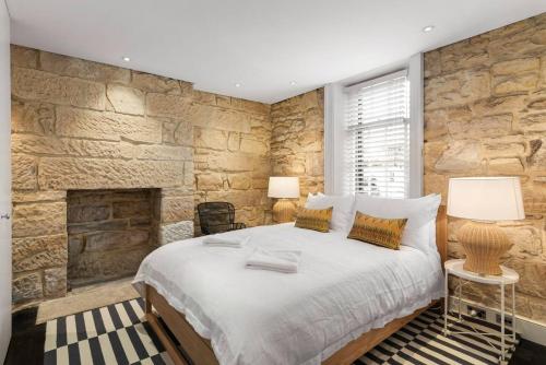 a bedroom with a large bed and a stone wall at Elegant Paddington Sandstone Cottage with Parking in Sydney