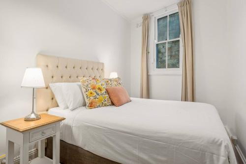 1 dormitorio con 1 cama blanca con lámpara y ventana en Harbourfront meets Heritage Chic near Barangaroo, en Sídney