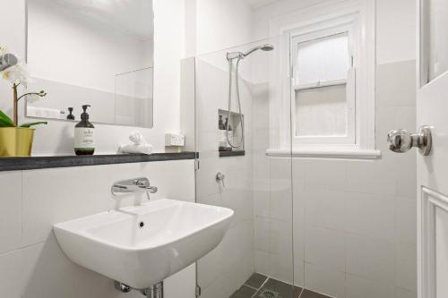 Un baño blanco con lavabo y ducha. en Harbourfront meets Heritage Chic near Barangaroo, en Sídney
