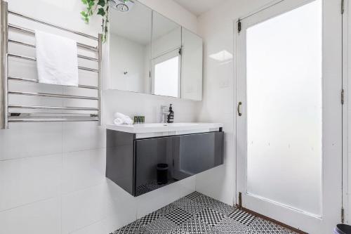 a white bathroom with a sink and a mirror at 'The Georgian' Classic Comfort in St Kilda's Heart in Melbourne
