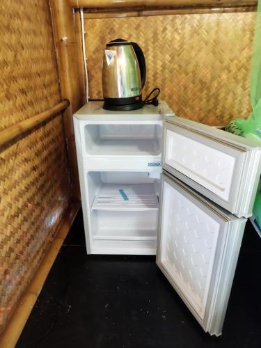 an open refrigerator with a tea kettle on top of it at Palm Garden Bungalow in Ko Lanta