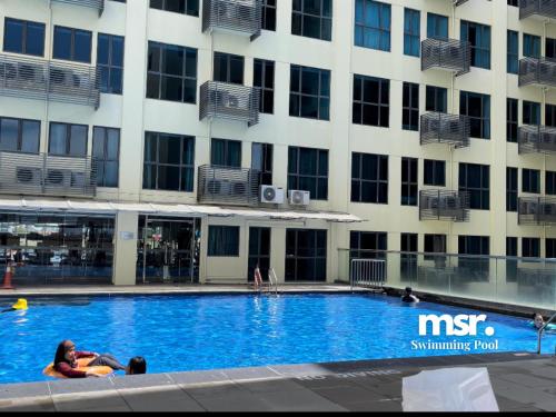 a woman laying in a swimming pool in front of a building at Kota Kinabalu City Ensuite at SCSP Ming Garden in Kota Kinabalu