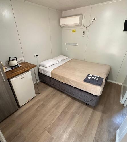 a small room with a bed and a night stand at Roebuck Plains Roadhouse in Broome