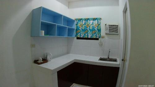 Elle comprend une petite cuisine avec des placards bleus et un évier. dans l'établissement LaVeranda Beach Resort, à Dauis