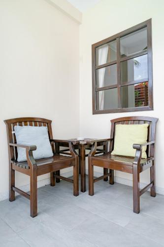 two wooden chairs and a table and a mirror at Naiya Buree Boutique Resort Nai Harn Beach in Rawai Beach