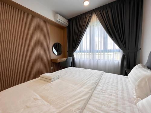 une chambre avec un grand lit blanc et une fenêtre dans l'établissement Cozy Loft at Sunway Onsen, à Kampong Batu Lapan