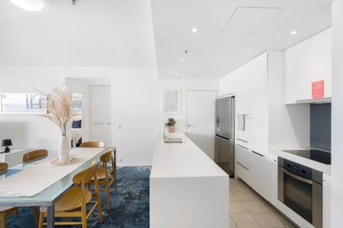 a kitchen with white cabinets and a table with chairs at Belle Escapes 24 Harbour Lights Water View Apartment in Cairns