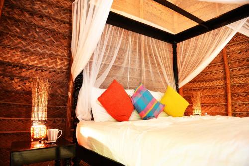 een slaapkamer met een bed met kleurrijke kussens bij Palagama Beach Resort in Kalpitiya