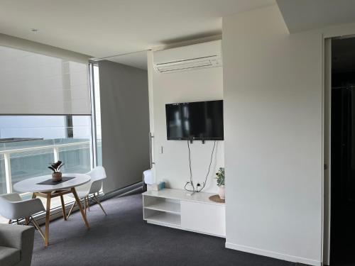 a living room with a table and a tv at Luxurious Apartments Near City in Adelaide