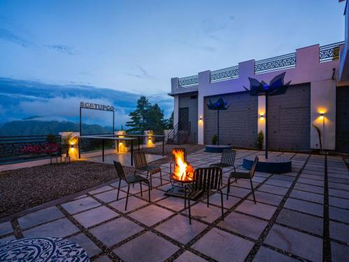 a patio with chairs and a fire pit at night at The Hosteller Chakrata in Chakrāta