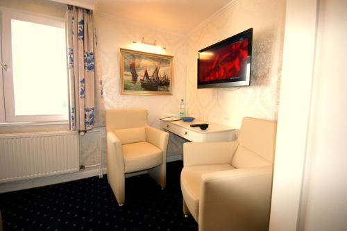 a bathroom with two white chairs and a sink at Hotel Beckröge in Cuxhaven