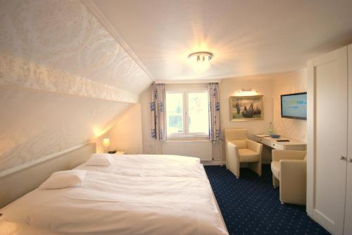 a hotel room with a white bed and a desk at Hotel Beckröge in Cuxhaven