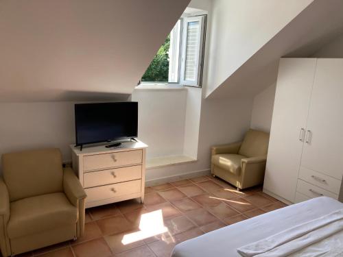 um quarto com uma cama, uma televisão e 2 cadeiras em guesthouse Libertas 1 em Dubrovnik