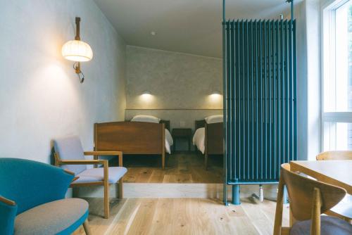 Cette chambre comprend deux lits, une table et des chaises. dans l'établissement haluta hotelli still, à Karuizawa