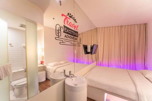 a hotel room with a bed and a bathroom with a sink at J Icon Hip Hotel in Balikpapan