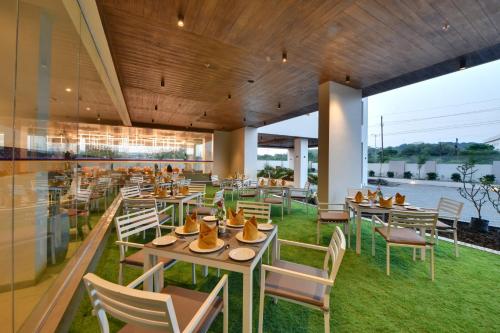 a restaurant with tables and chairs with a view of the water at Click Hotel Pithampur in Mhow