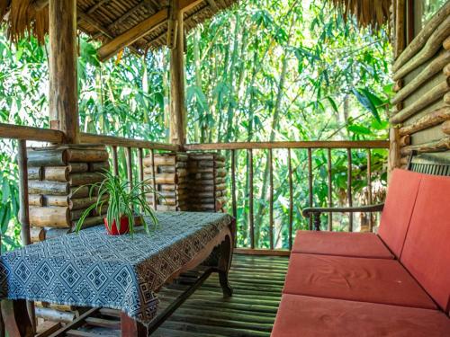 a wooden porch with a table and a red chair at Pu Luong Jungle Lodge in Pu Luong