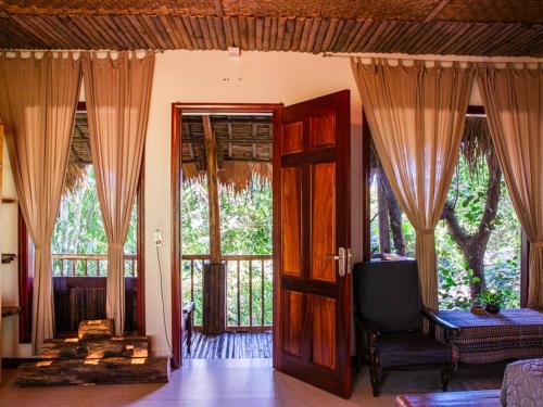 a living room with curtains and a door and a chair at Pu Luong Jungle Lodge in Pu Luong