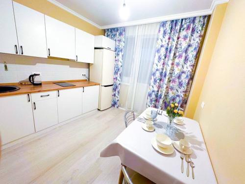 uma pequena cozinha com uma mesa branca e uma mesa e cadeiras brancas em New 1 bedroom рядом ханшатыр em Astana