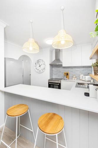 a kitchen with white cabinets and two wooden stools at Coastal convenience! Walk to the shops & cafes... in Perth