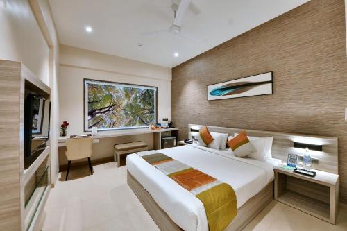 a hotel room with a bed and a desk and a window at Click Hotel Pithampur in Mhow