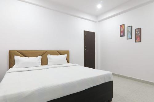 a white bedroom with a large bed with white sheets at KPS inn in Lucknow