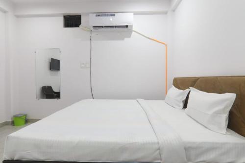 a bedroom with a white bed with a tv on the wall at KPS inn in Lucknow