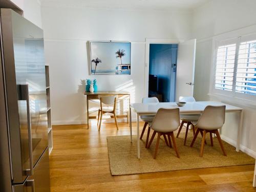 une salle à manger avec une table et des chaises blanches dans l'établissement Family Getaway to Manly Beach plus free onsite parking, stroll to beach, cafes, à Sydney