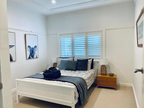 een witte slaapkamer met een bed met blauwe kussens bij Family Getaway to Manly Beach plus free onsite parking, stroll to beach, cafes in Sydney