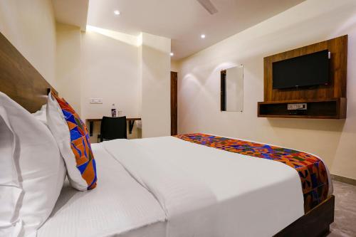 a bedroom with a white bed with a tv on the wall at FabExpress Antlers - Nr Boriwali in Mumbai