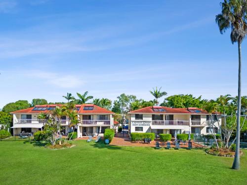 a resort with a green lawn and palm trees at Cayman Quays in Noosaville