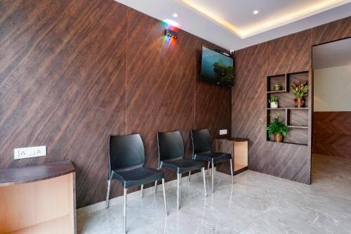 a waiting room with four chairs and a television on a wall at FabExpress Antlers - Nr Boriwali in Mumbai