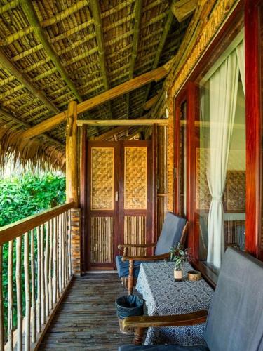 a porch of a resort with two chairs and a table at Pu Luong Jungle Lodge in Pu Luong