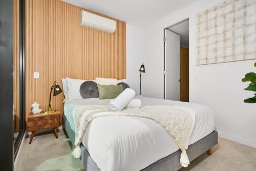 ein Schlafzimmer mit einem großen Bett mit weißer Bettwäsche in der Unterkunft Modern Elegance 2BR Luxury Apartment with Gym & Pool in Melbourne
