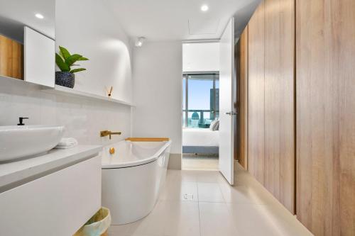 een witte badkamer met een bad en een wastafel bij Modern Elegance 2BR Luxury Apartment with Gym & Pool in Melbourne