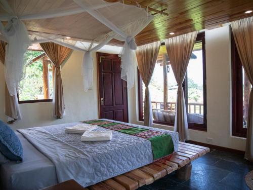a bedroom with a bed in a room with windows at Pu Luong Jungle Lodge in Pu Luong