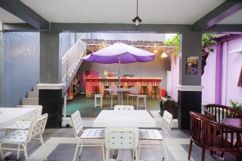 um restaurante com mesas e cadeiras e um guarda-sol roxo em Janna Guest House SYARIAH Yogyakarta Mitra RedDoorz em Yogyakarta
