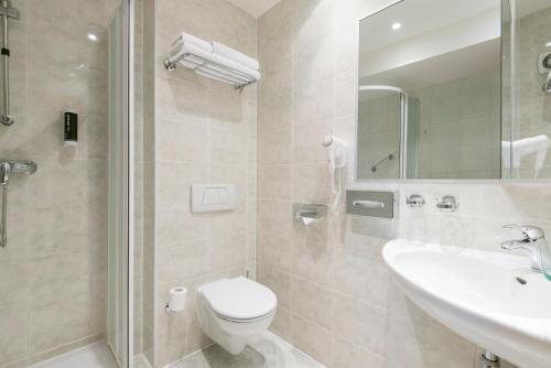 a bathroom with a toilet and a sink and a shower at Hotel Troja in Prague