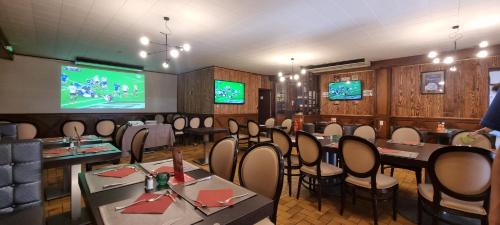 comedor con mesas y sillas y TV en Auberge du Bois de l'étang - Motel les Tilleuls en Peyrat-le-Château