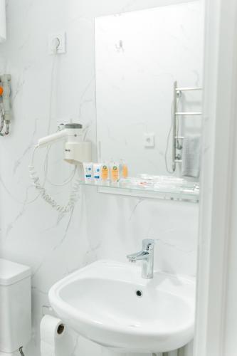 a white bathroom with a sink and a toilet at Жемчужина гостиница Балхаш in Balqash