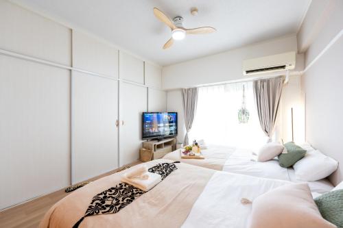 1 dormitorio con 2 camas y TV en Beige, en Tokio