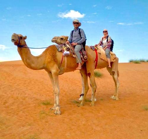 two people riding on a camel in the desert at Al Salam Desert Camp Bidiya in Bidiyah