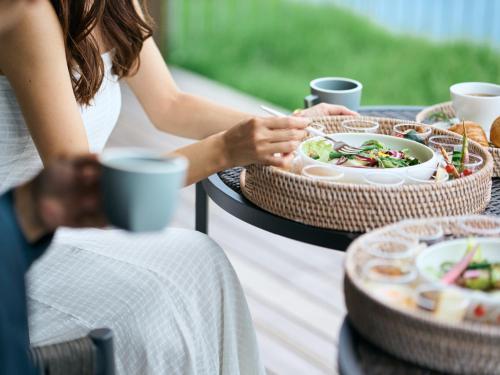 a woman is sitting at a table with a meal at YANMAR SUNSET MARINA CLUBHOUSE&HOTEL in Moriyama