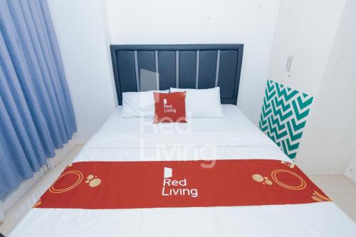 een bed in een kamer met een rood woonbord erop bij Redliving Apartemen Grand Sentraland - AT Properti Tower Pink in Karawang