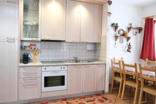 a kitchen with white cabinets and a sink at Al Ruscello in Canazei