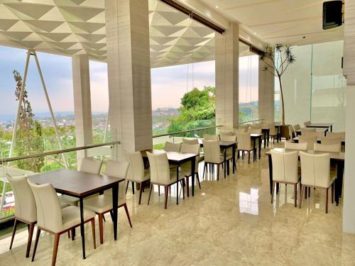 a restaurant with tables and chairs and large windows at Sinergi Hotel & Villa in Sengkaling