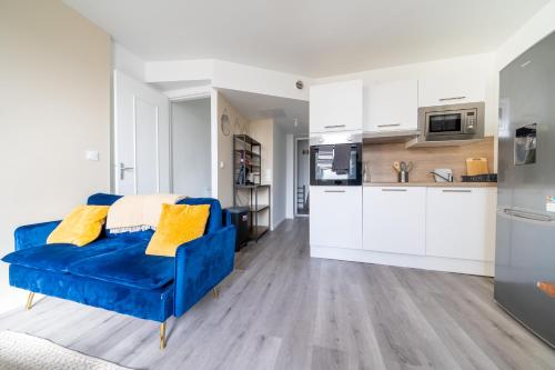 un canapé bleu dans une cuisine avec des placards blancs dans l'établissement Maison 4 ch, idéal déplacement pro, parking, rénové, à Rouen