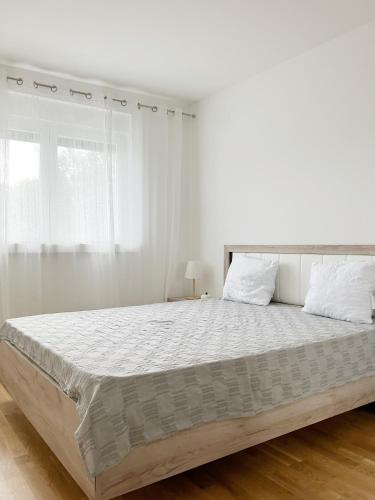 een witte slaapkamer met een groot bed met witte lakens bij Don Balkan Apple in Vrnjačka Banja